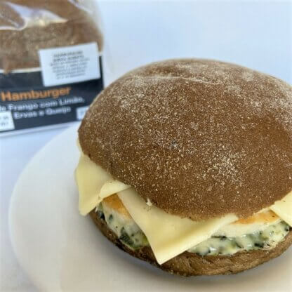 foto de sanduiche de hamburguer de frango com limão, ervas e queijo no prato com embalagem ao fundo